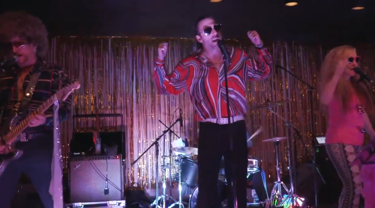 Lead male singing for 70s disco tribute band wearing patterned long sleeved shirt performing center stage alongside two other artists | Altus Entertainment