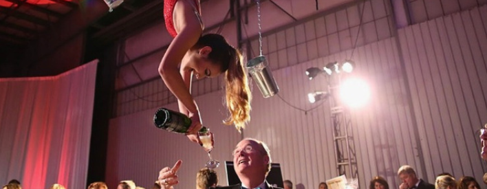 Female aerial bartender in Arizona pouring drink into glass for attendee while smiling happily | Altus Entertainment
